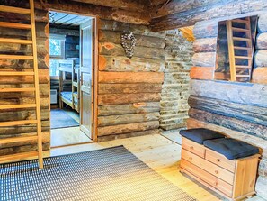 A log cabin interior with bunk beds, a wooden dresser, and a stone wall.