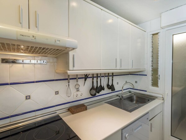 Een moderne keuken met witte kastjes, een roestvrijstalen spoelbak en een inbouwoven.