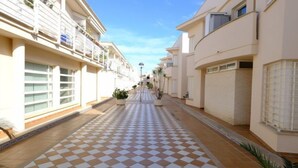 Une rue étroite au pavé à carreaux, bordée de bâtiments des deux côtés.