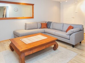 A living room with a grey sofa, wooden coffee table, and a mirror on the wall. - Muuttohaukka by Interhome (Kuusamo)
