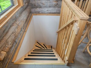Una escalera de madera que lleva a una habitación con ventana y vistas al exterior.