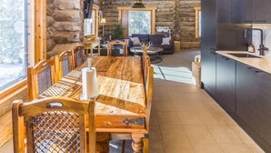 A log cabin interior with a dining area, kitchen, and living room.