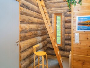 A log cabin interior with a wooden ladder, a window, a stool, and a wall-mounted light switch. - Muuttohaukka by Interhome (Kuusamo)