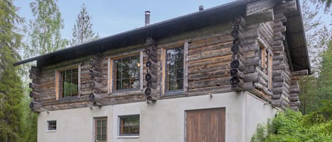 Une cabane en rondins à deux étages, dotée de grandes fenêtres et d’une porte.