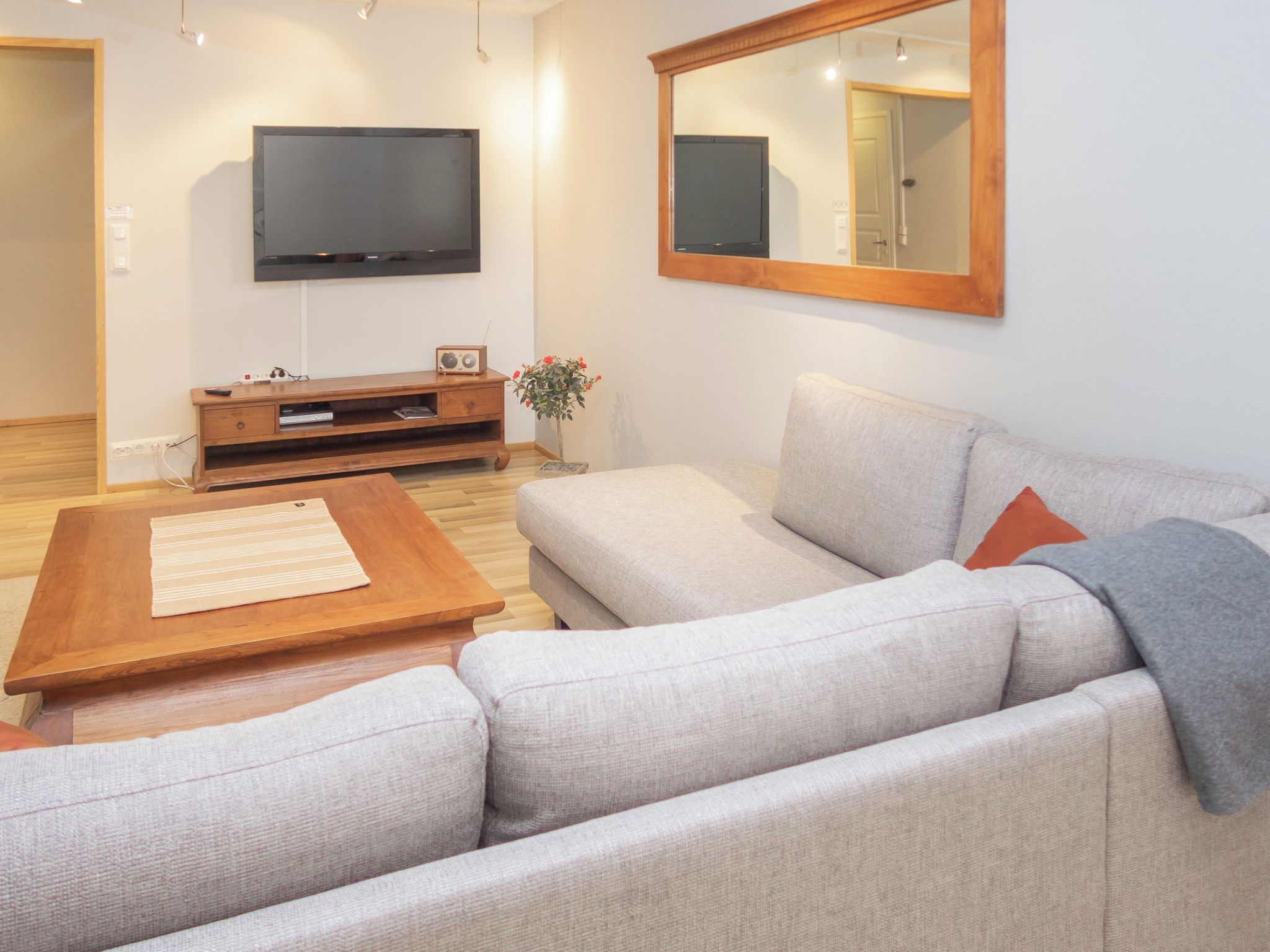 Een woonkamer met een bank, een salontafel, een televisie en een houten kast.