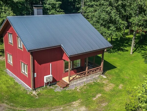 A red two-story house with a metal roof and a wooden porch. - Långstrands stuga by Interhome (Raasepori)