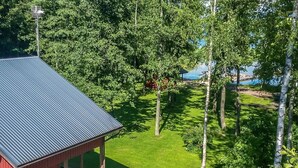 A cabin with a metal roof, surrounded by a well-maintained lawn and tall trees. - Långstrands stuga by Interhome (Raasepori)