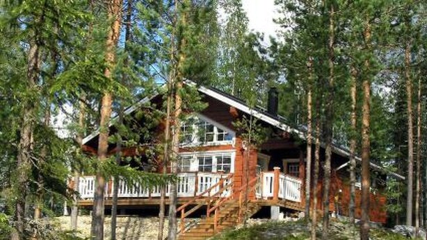 Une cabane avec une façade en bois, une terrasse et un escalier menant à l’entrée principale.