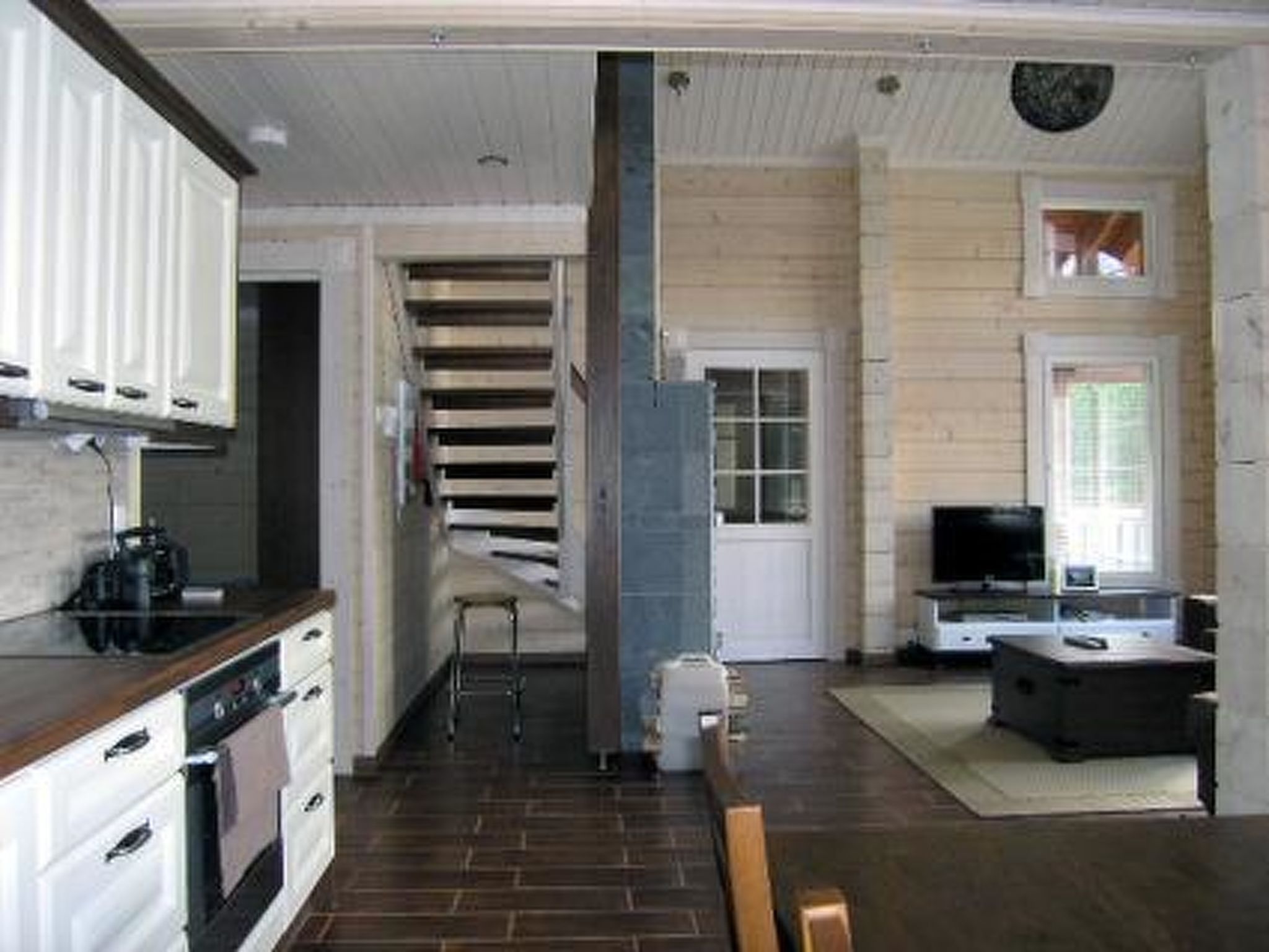 A compact kitchen with modern appliances, a dining area with a TV, and a staircase leading to another level.