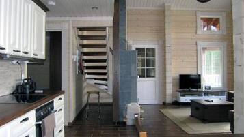 A compact kitchen with modern appliances, a dining area with a TV, and a staircase leading to another level.