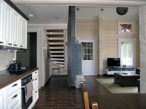 A compact kitchen with modern appliances, a dining area with a TV, and a staircase leading to another level. - Syvälahti by Interhome (Sonkajärvi)
