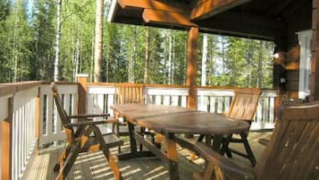 A wooden deck with a table and chairs, surrounded by trees.