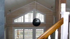 Une pièce dotée d’un plafond en pente, de poutres en bois, d’un escalier en bois et de grandes fenêtres.