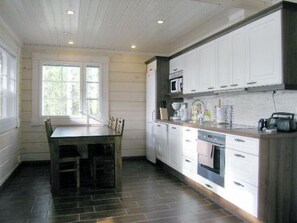 Una cocina con armarios blancos, una mesa de comedor de madera y un ventanal.