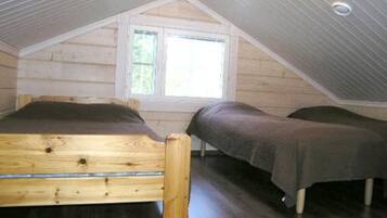 A bedroom with a sloped ceiling, a wooden bed, a window, and a small table.