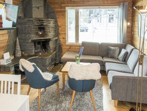 Un salon chaleureux avec une cheminée en pierre, un ensemble de canapés et un téléviseur.