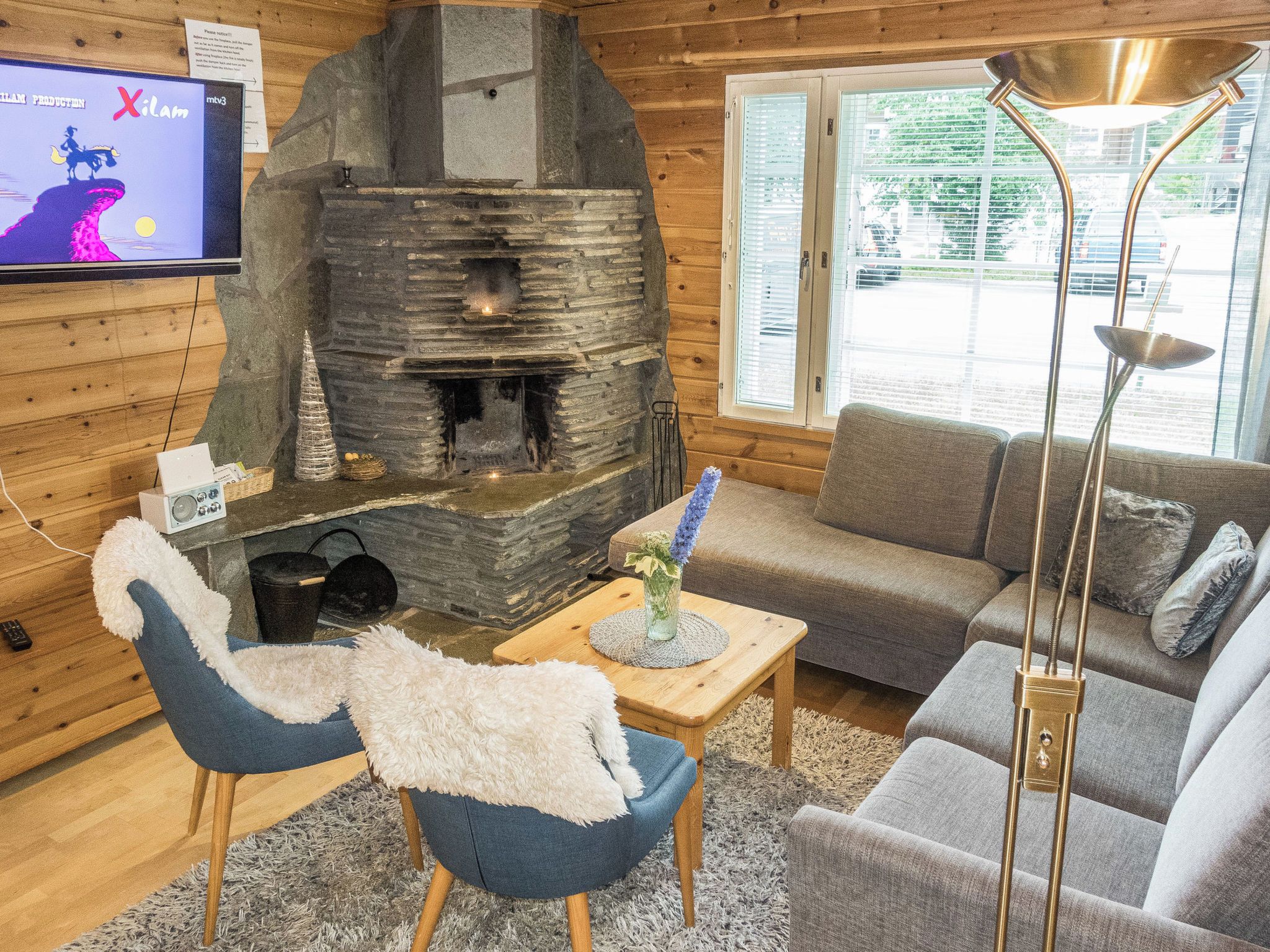 Een gezellige woonkamer met een stenen open haard, een televisie en een bank.
