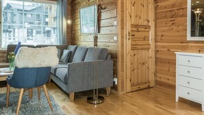 Une pièce chaleureuse avec un canapé gris, un fauteuil bleu, une commode blanche et un grand lampadaire.