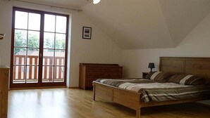 Un dormitorio con una cama de madera, una mesita de noche, un aparador y una puerta corrediza de cristal que da a un balcón.