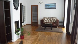 Una sala de estar con un sofá marrón, una mesa de centro, una planta en maceta y un cuadro en la pared.