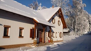 Un edificio cubierto de nieve con techo inclinado, vigas de madera y un porche.