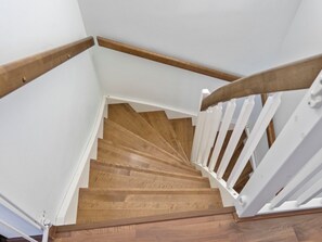 Eine Holztreppe mit weißen Geländern und einer weißen Wand.
