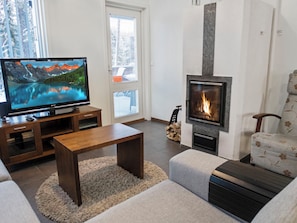 A living room with a television, a fireplace, a sofa, and a coffee table. - Vuokatinlampi 7 a by Interhome (Sotkamo)