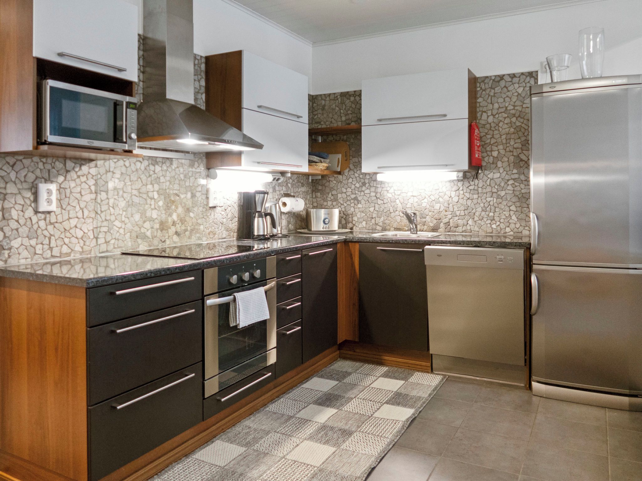 Een moderne keuken met een inbouwoven, magnetron en een koelkast van roestvrij staal.