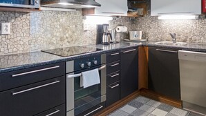 Eine moderne Küche mit Granit-Arbeitsplatten, einem Backofen, einer Kaffeemaschine und einem Geschirrspüler.