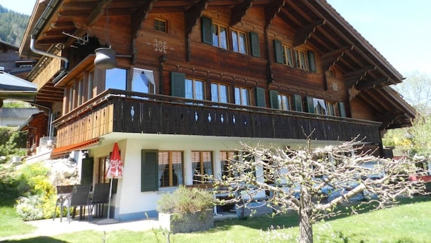 A traditional wooden chalet with a balcony, surrounded by greenery. - Apartment Bolgen by Interhome (Zweisimmen)
