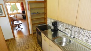 A compact kitchen with a herringbone floor pattern, a sink, a coffee maker, and a dishwasher. - Apartment Bolgen by Interhome (Zweisimmen)