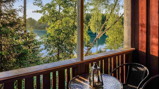 Un balcon en bois avec une table en verre, une chaise et une lanterne.