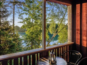 A wooden deck with a table and chairs, overlooking a lake surrounded by trees. - Isokoskelo 5 by Interhome (Parainen)