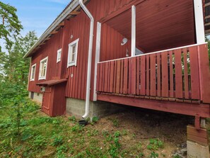 A red wooden house with a porch, a small attached shed, and a garden area. - Isokoskelo 5 by Interhome (Parainen)