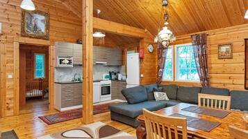 Ein Holzblockhaus-Interieur mit Essbereich, Küche und Wohnzimmer mit einer Couch.