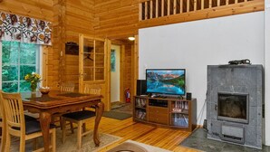 L'intérieur d'un chalet en bois comprend un coin repas, un téléviseur et une cheminée.