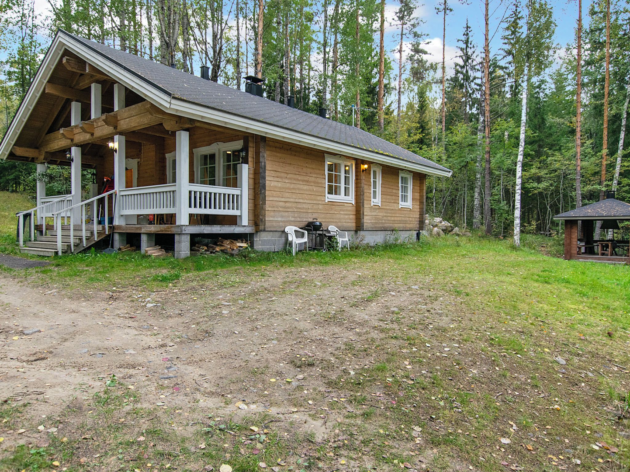 A wooden cabin with a porch, a small deck, and a fireplace.