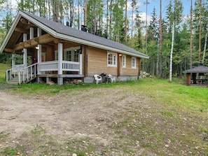 A wooden cabin with a porch, a small deck, and a fireplace.