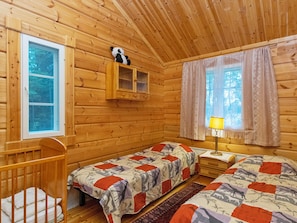 A cabin with two beds, a wooden crib, a window, and a cabinet with a stuffed panda. - Mökki mikkola by Interhome (Mikkeli)
