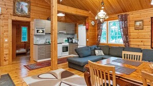 Un intérieur chaleureux de chalet en bois, comprenant un coin repas, une cuisine et un salon.
