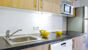 A kitchen with a stainless steel sink, two yellow bowls, a microwave, and a dishwasher. - Gentiane by Interhome (Chamonix)