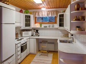 A compact kitchen with white cabinets, a microwave, a stove, and a sink.