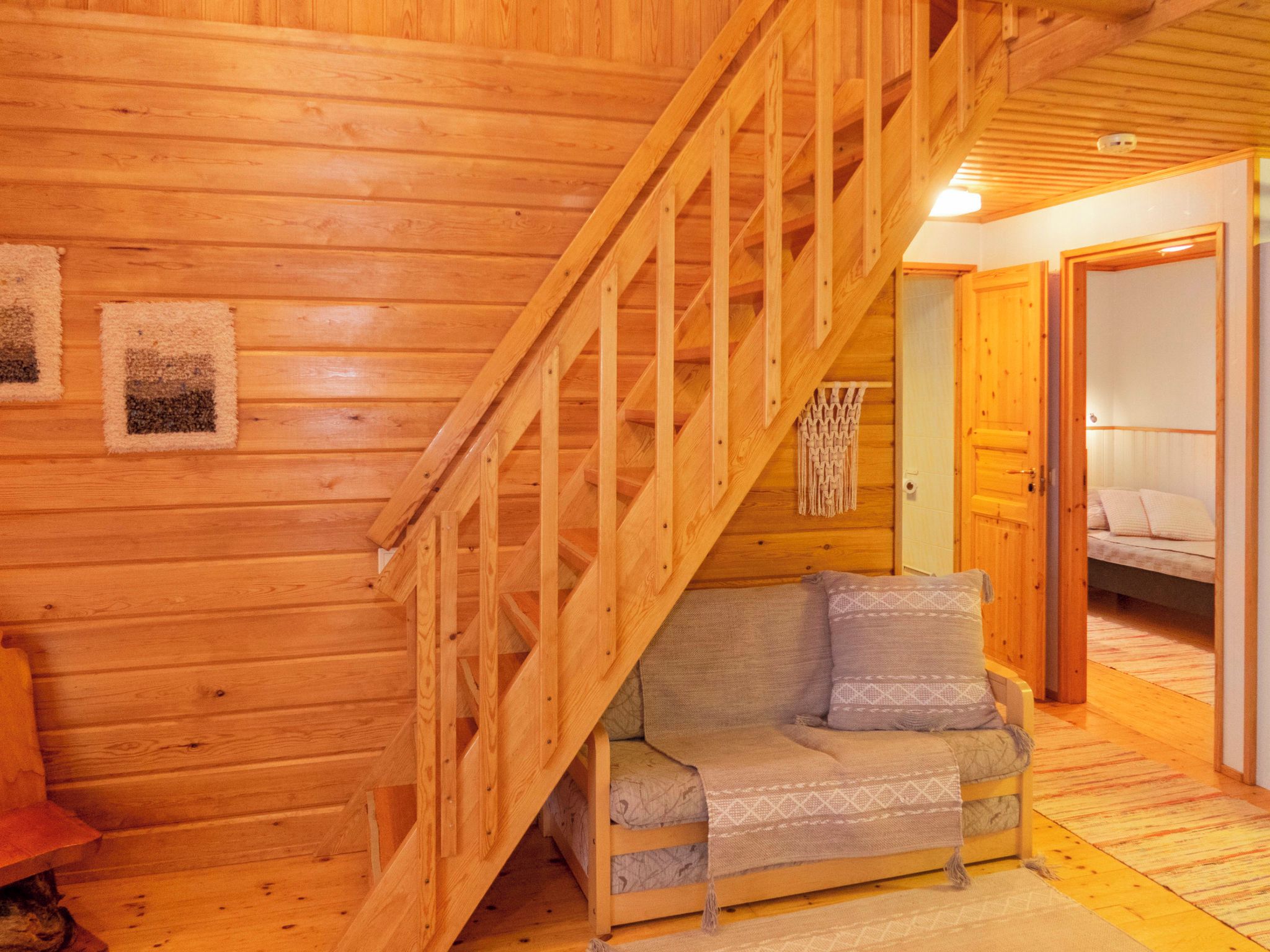 A wooden interior with a staircase, a sofa, and a bed.