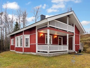 A two-story cabin with a balcony, a front porch, and a chimney. - Pesäkolo by Interhome (Kuusamo)