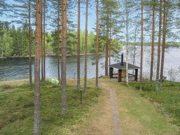 Eine Hütte am See, umgeben von hohen Bäumen.