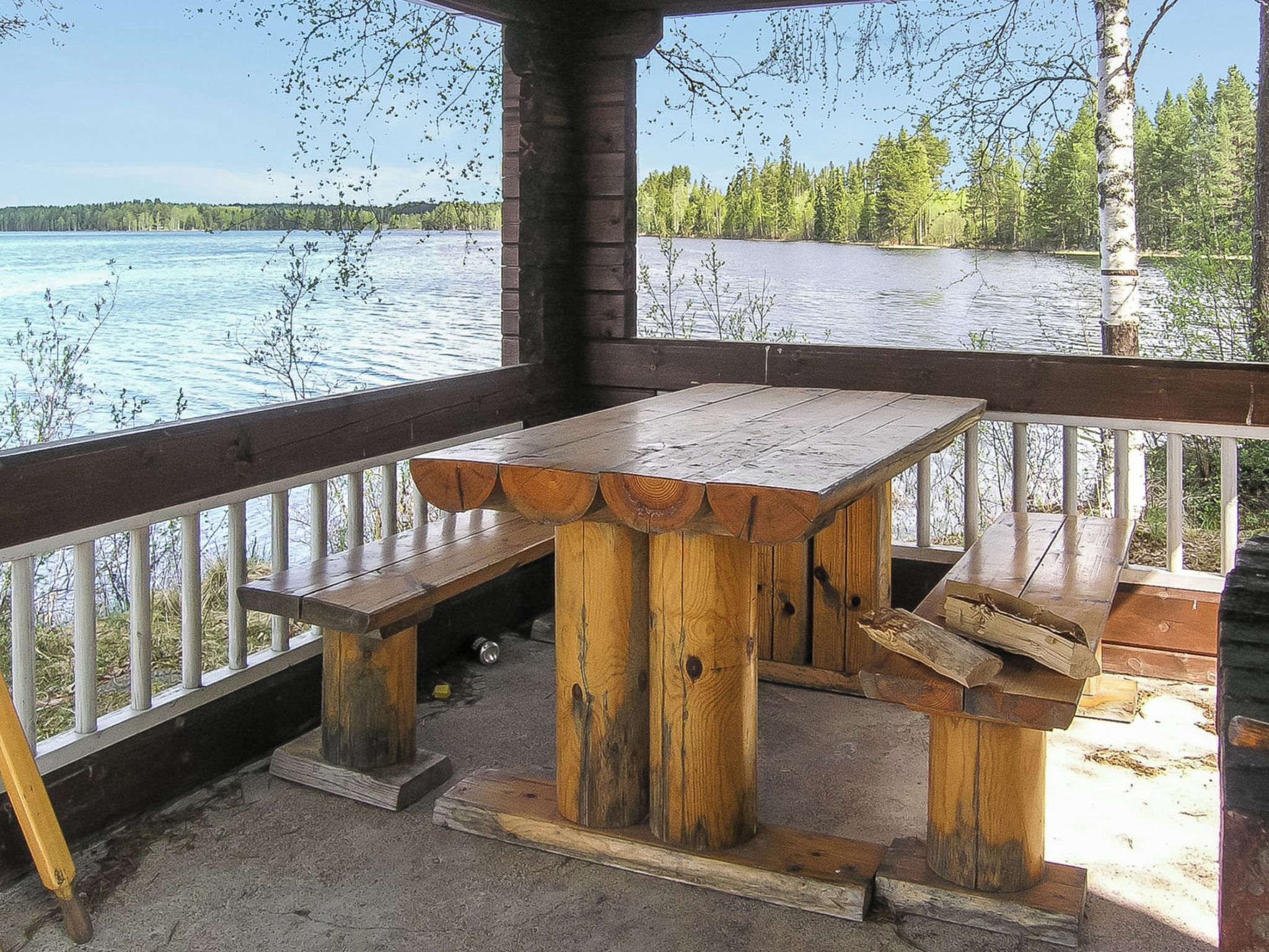 A wooden deck with a bench and picnic table overlooking a lake.