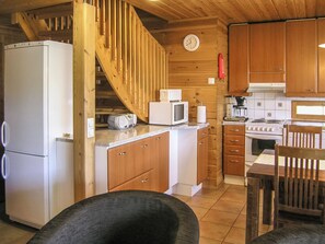 Eine kompakte Küche mit Holzausstattung, einer eingebauten Mikrowelle, einem Herd und einem Kühlschrank.