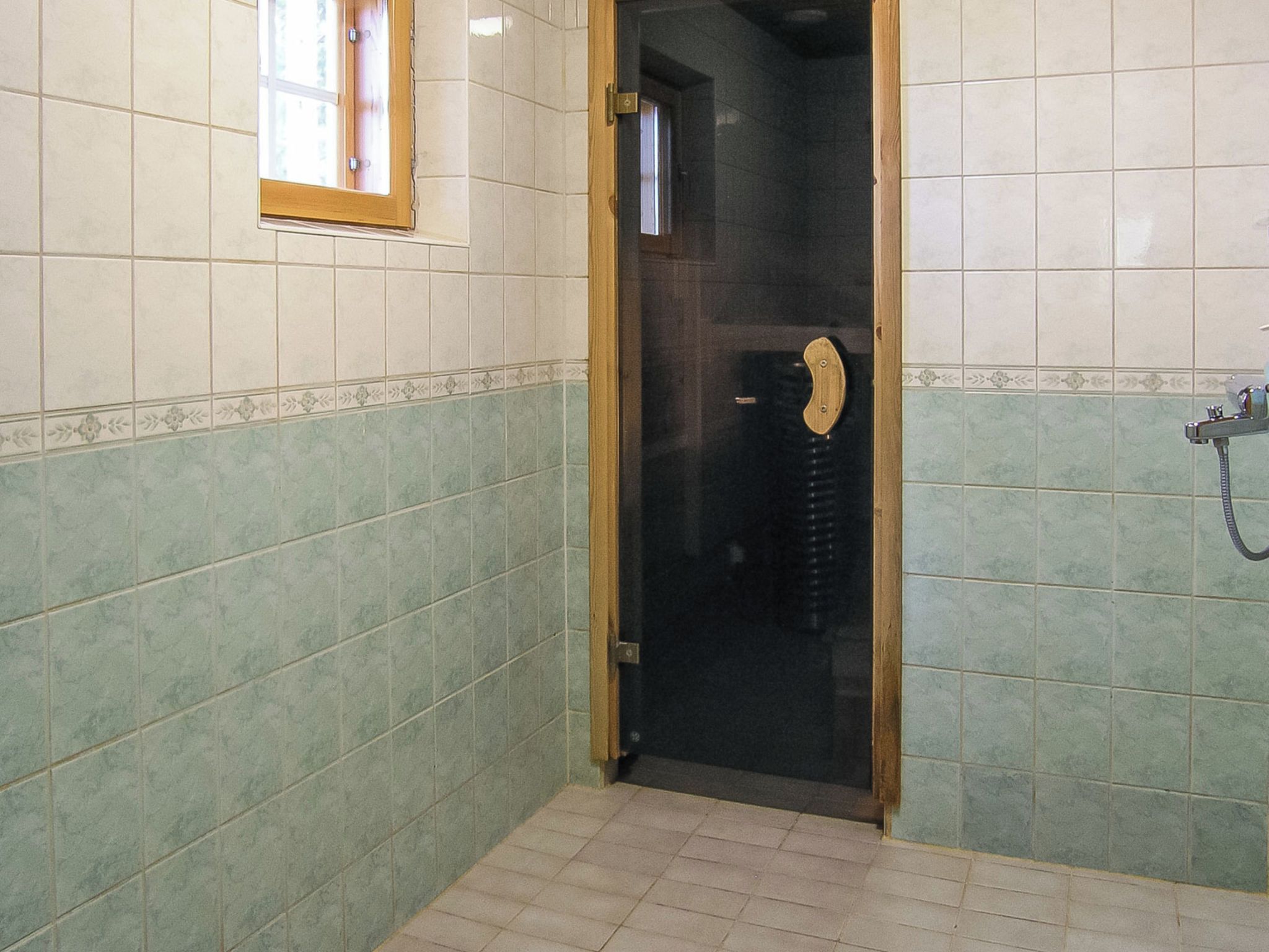 Un baño con puerta de vidrio, paredes con azulejos y zona de ducha.