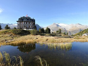 A traditional chalet with a view of mountains and a lake.