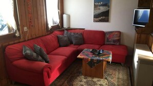 A cozy living room with a red sofa, a patterned rug, and a painting on the wall.